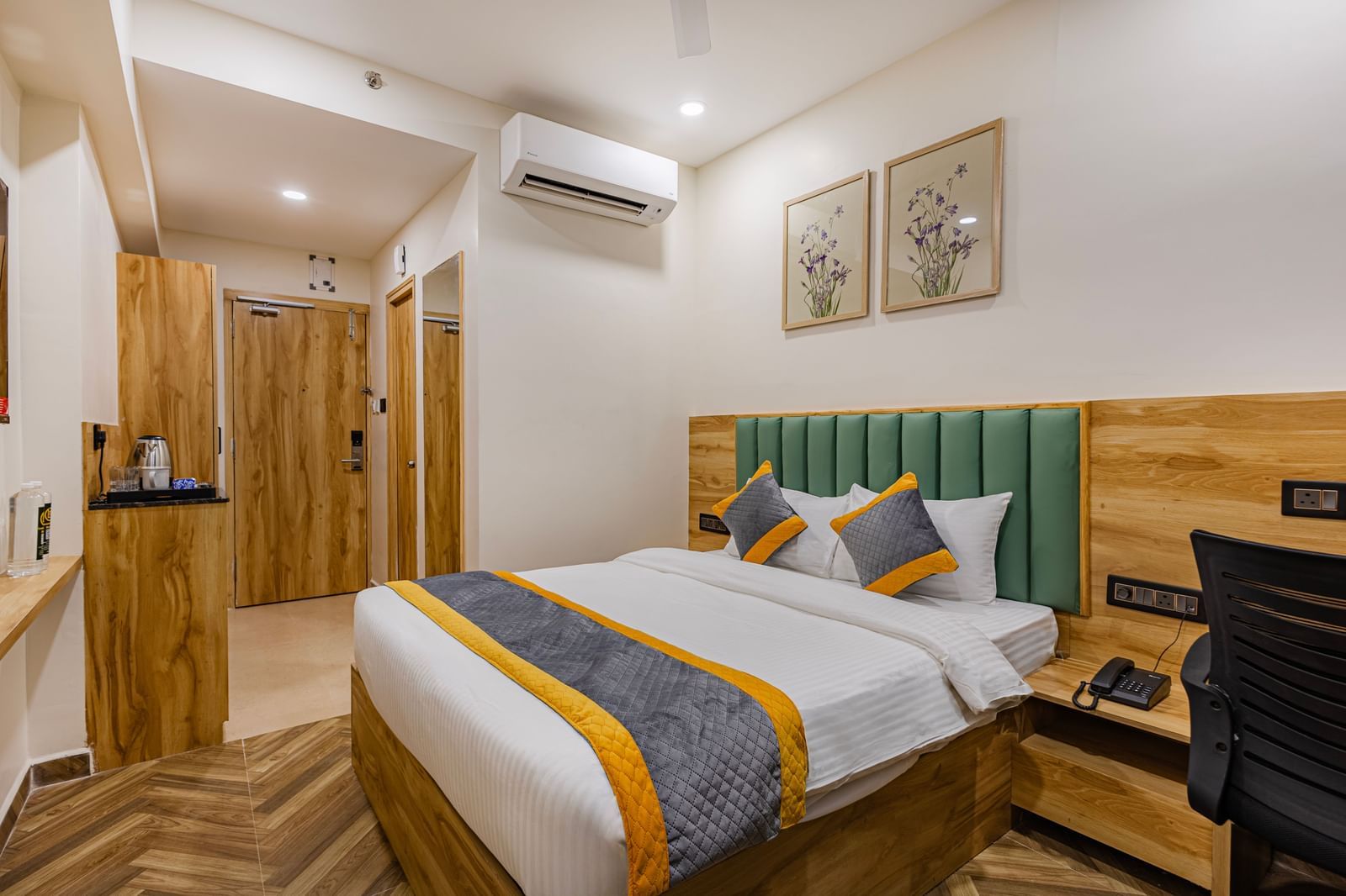 Cozy Room with double bed, green cushioned headboard, wooden furniture, desk with chair, air conditioning, and warm ambient lighting at Lemonridge Hotels, KPHB